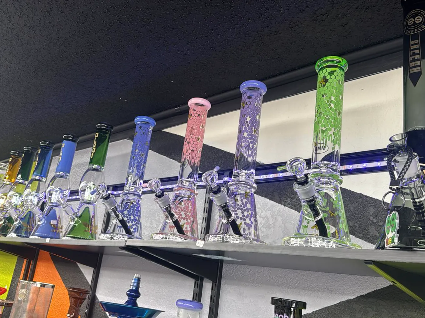 A row of coloured beaker water pipes along the top shelf